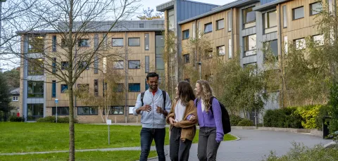 Three students walking outside halls of residence