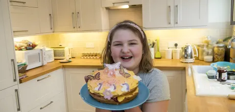 Belle shows off a decorated cake in a bright, modern kitchen