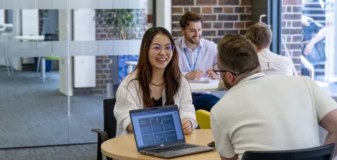 A student discussing fees with a university advisor. Another student and advisor talking are in the background.