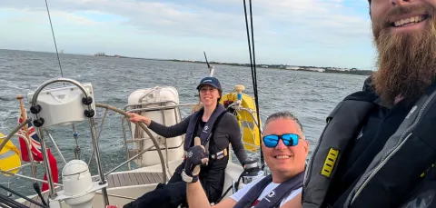 Participants on a sailing session out on the water smiling taking a selfie
