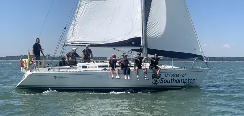Crew sitting on the side of a yacht sailing on the sea.