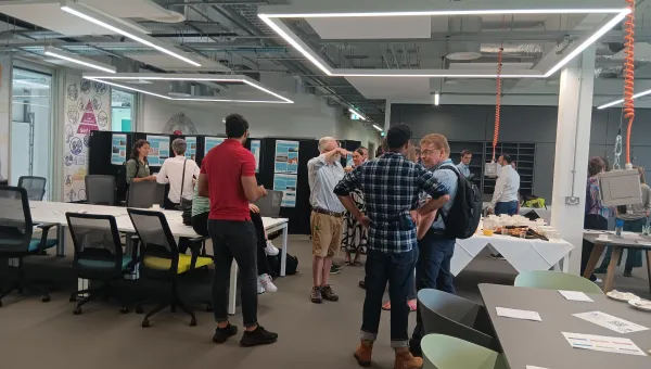 Modern office space with several people engaged in conversation around a table filled with refreshments. 