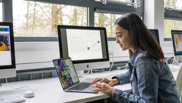 A student working on a laptop in the Wimnchester school of art fashion design studio