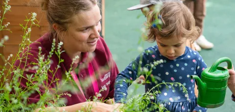 Early Years Centre carer with child watering plants