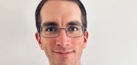Matthew Blunt, looking directly at the camera in a navy suit with a light blue shirt.