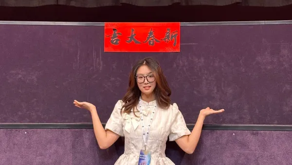 Shuheng Zhand standing in front of a banner in Chinese