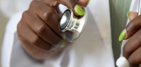 A healthcare student with a clean white lab coat readies their stethoscope