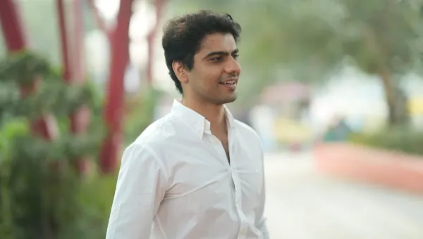 Law graduate and entrepreneur Rohit is standing looking to the right of the camera. There are out of focus trees and shrubs behind him.