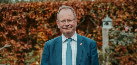 Professor Sir Stephen Holgate, stood in front of an autumnal hedge.