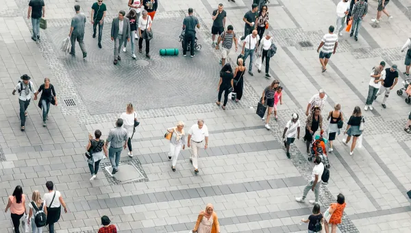 An aerial view of crowds of people walking in an urban environment.