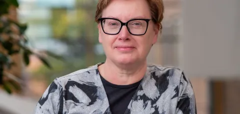Fiona leaning against a low wall. She's looking into the camera and smiling for the photo.