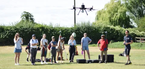 A group of people out on a field using an aerial drone.