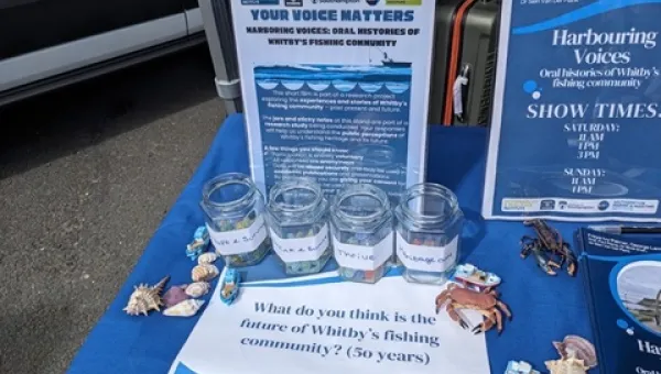Display of glass jars with labels and maritime decorations on a table, accompanied by informational signs about Whitby’s fishing community.
