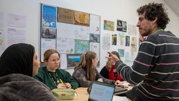 Teacher leading a small classroom discussion with several students seated around a table.