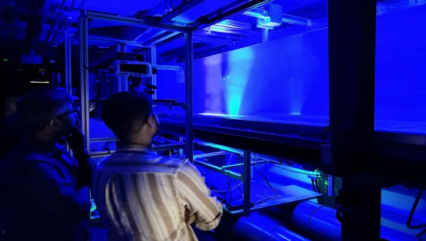 Researchers observing illuminated airflow patterns during an experimental fluid mechanics test