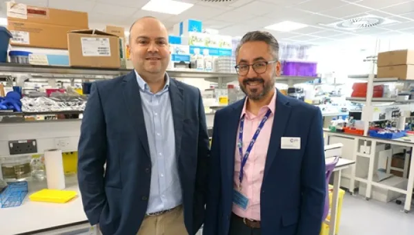 Salah Mansour and Ali Roghanian standing together in a lab, both are wearinf blue jackets.