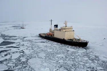 A ship surrouded by ice next to a small vassel.