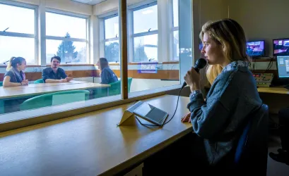 A researcher directs participants of an observation study behind a 2 way mirror