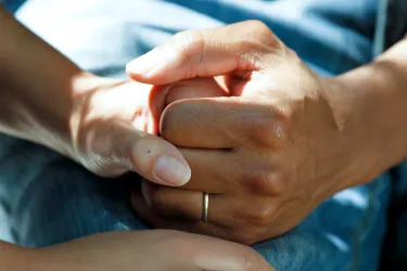 Comforting hands on a hospital bed