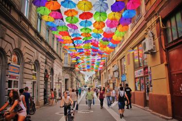 Image of a back street with lots of colourful umbrellas hanging above it on string.