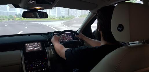 Student with both hands on the wheel of a driving simulator