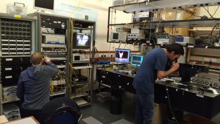 Two researchers from the optical fibre communications group at work against a backdrop of complex equipment 