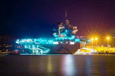 Aircraft carrier lit up at night in dock