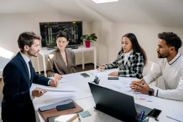 Group of 4 people talking around a work table