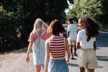 Teenagers walking down a sunny country lane away from the camera