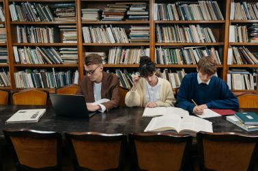 Three young researchers in an old library taking notes