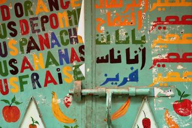 Closed metallic door of a shop with coloured words in French and Arabic about juices