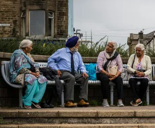 4 people from the Bangladeshi and Pakistani communities sitting on a bench talking