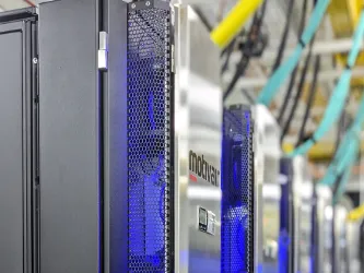 IRIDIS 6 research computing facility - a bank of servers in silver casing with yellow and blue network cables in the background