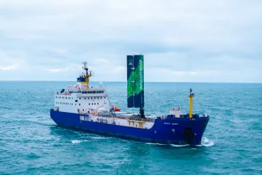 A large cargo vessel sailing on the ocean. It has a 20 metre-high wing sail. 