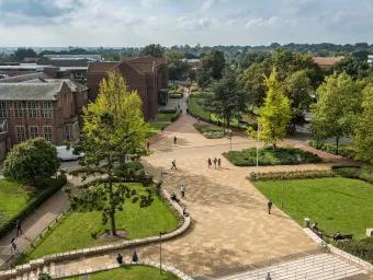 Aerial view of campus buildings, trees and courtyard area on a sunny day.