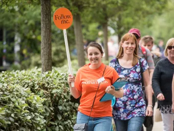 A student leads visitors on a tour of campus at an open day.