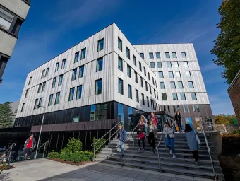 Students outside modern campus building on a sunny day.