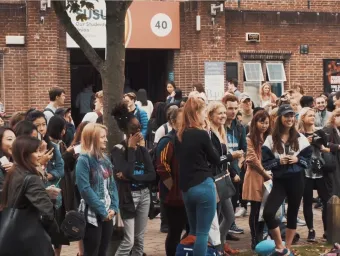 Large group of students gathered outside the Students' Union building.