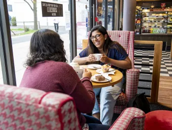 2 students in Costa chatting over a drink.