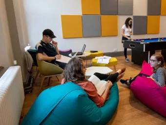Group of students in common room, sat talking and playing pool.