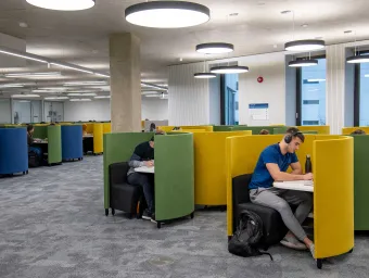 Students working in individual study pods, in a modern building.