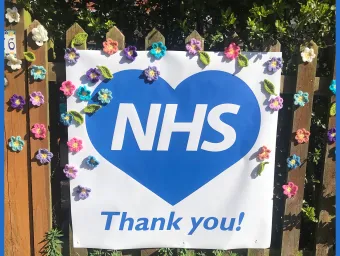 Thank you NHS sign decorated with flowers on garden gate.