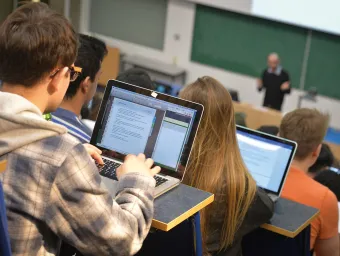 Students in lecture theatre writing notes on laptops