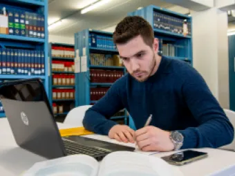 A male student studying at his laptop in the library.