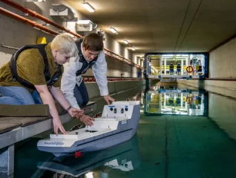 Two students test a model boat in the towing tank