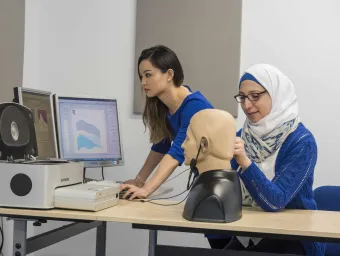 2 students conducting a hearing test on a dummy.
