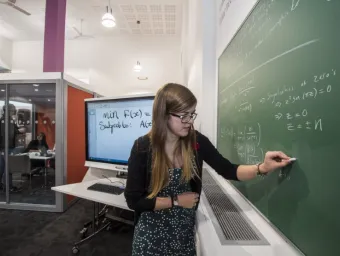 A student works on a maths problem using a blackboard in the maths student centre.