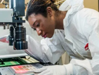 A researcher leaning over to observe the contents of a slide under a powerful microscope.