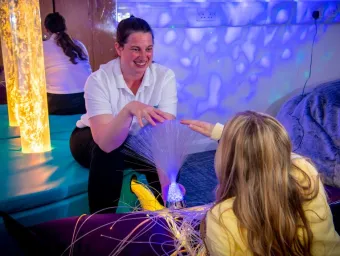 A healthcare students works with their young client in the multisensory room