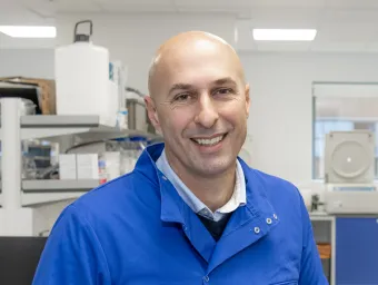 Dr Stephen Beers, wears blue protective gear in a laboratory